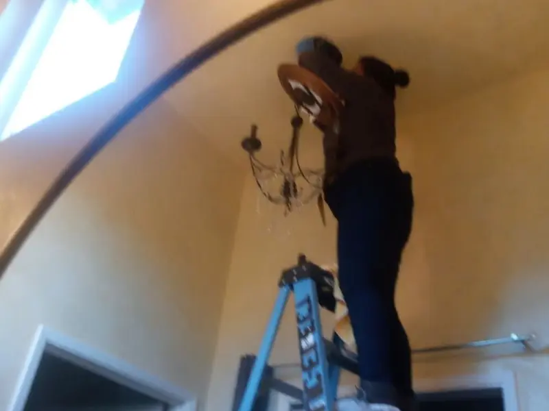 Electrician installing a chandelier in a Hope residence